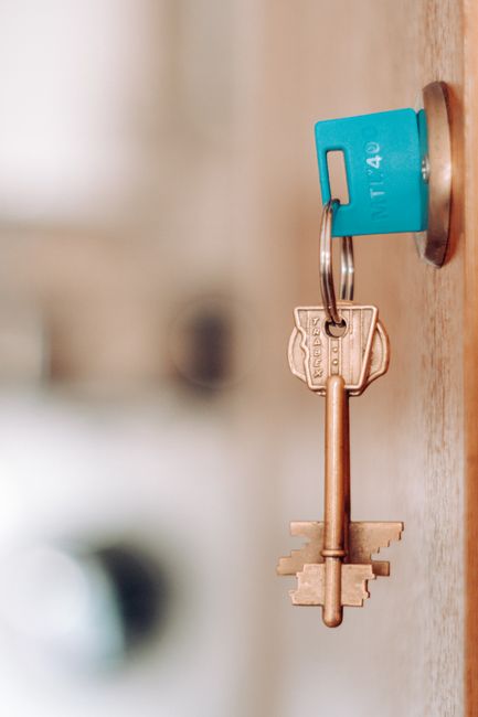 A flat surface showing various items used in home relocation planning and packing, including a roll of black tape, a black marker pen, a set of house keys attached to a keyring with a small house-shap